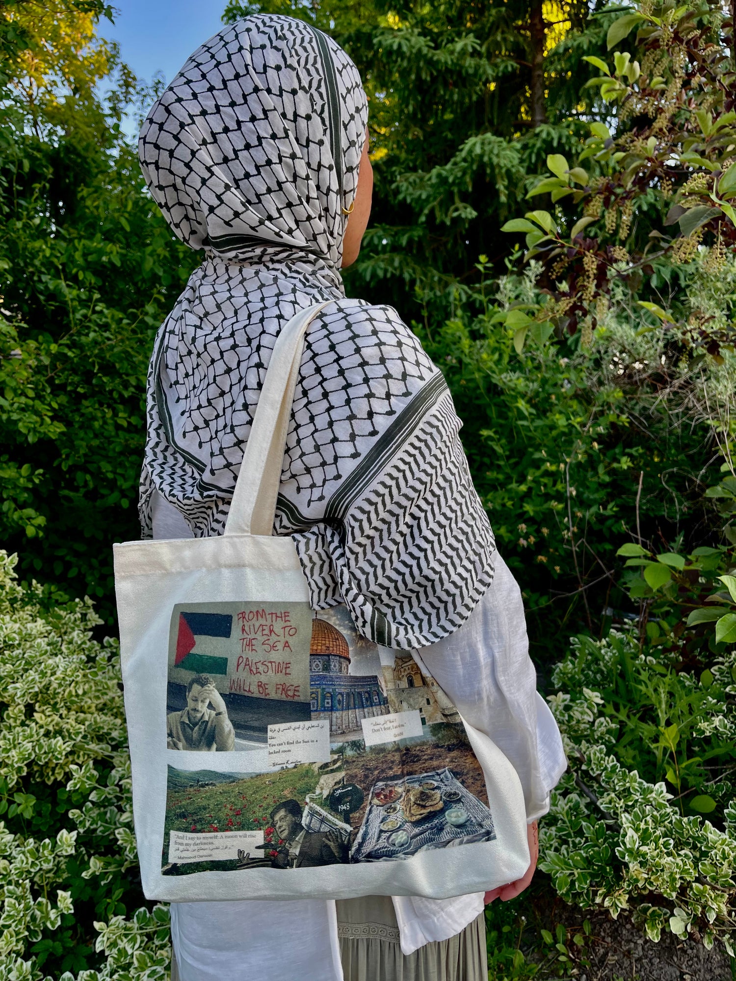 Muslim woman holding a Palestine tote bag with original collage design in a garden.